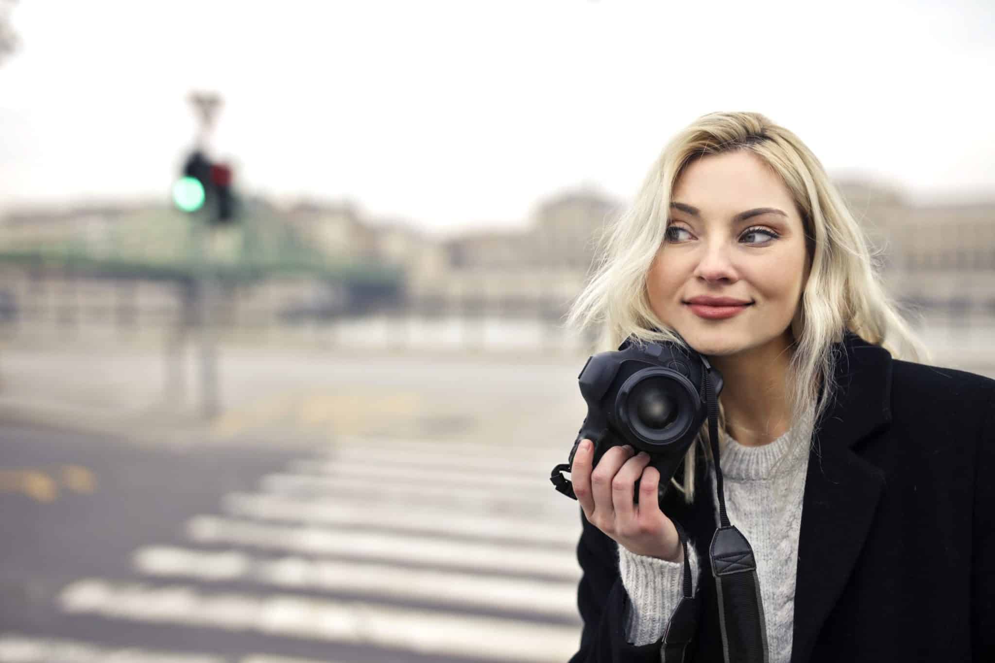 Eine junge Frau mit Kamera erkundet die Straßen, auf der Suche nach lebendigen Momenten. Bei LET IT CLICK verwandeln wir solche Augenblicke in unvergessliche Fotoshootings.