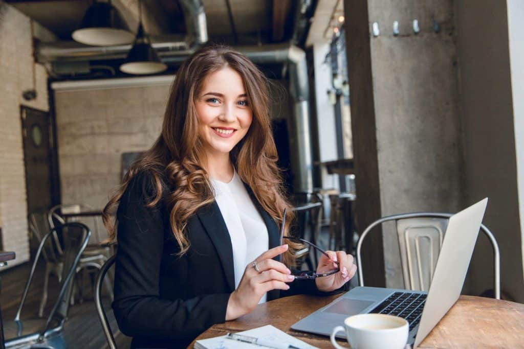 Praktikum bei LET IT CLICK als Sales und Business Developer: Engagierte Frau in Businesskleidung mit Laptop und lächelndem Gesicht