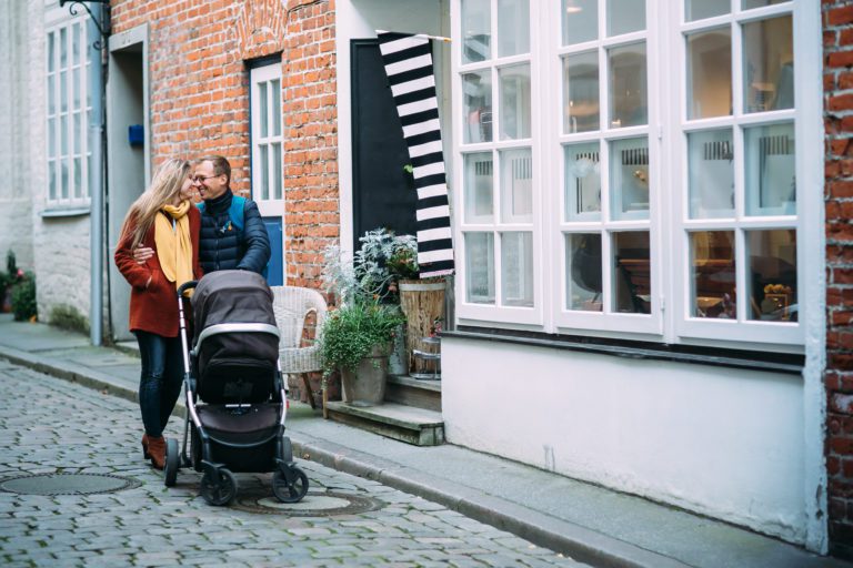 Fotografen in Lübeck. Eltern spazieren mit Kind im Kinderwagen durch die Straßen. Sie sind glücklich. Hoffentlich.