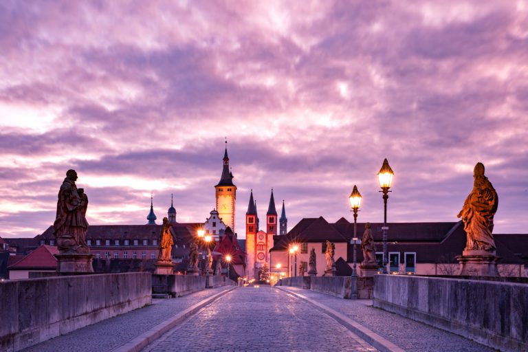 Old Main Bridge, Alte Mainbrucke with statues of saints, Cathedral and City Hall in Old Town at pink sunset, Wurzburg, Bavaria, Germany