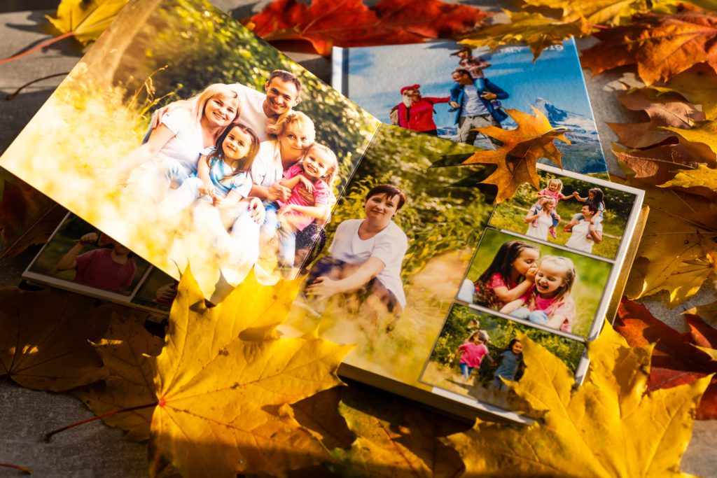 Ein Fotoalbum dekoriert mit Herbstblättern. Auf den Fotos ist eine glückliche Familie zu sehen, während kleinere Bilder fröhliche Kinder zeigen, die den Moment genießen.