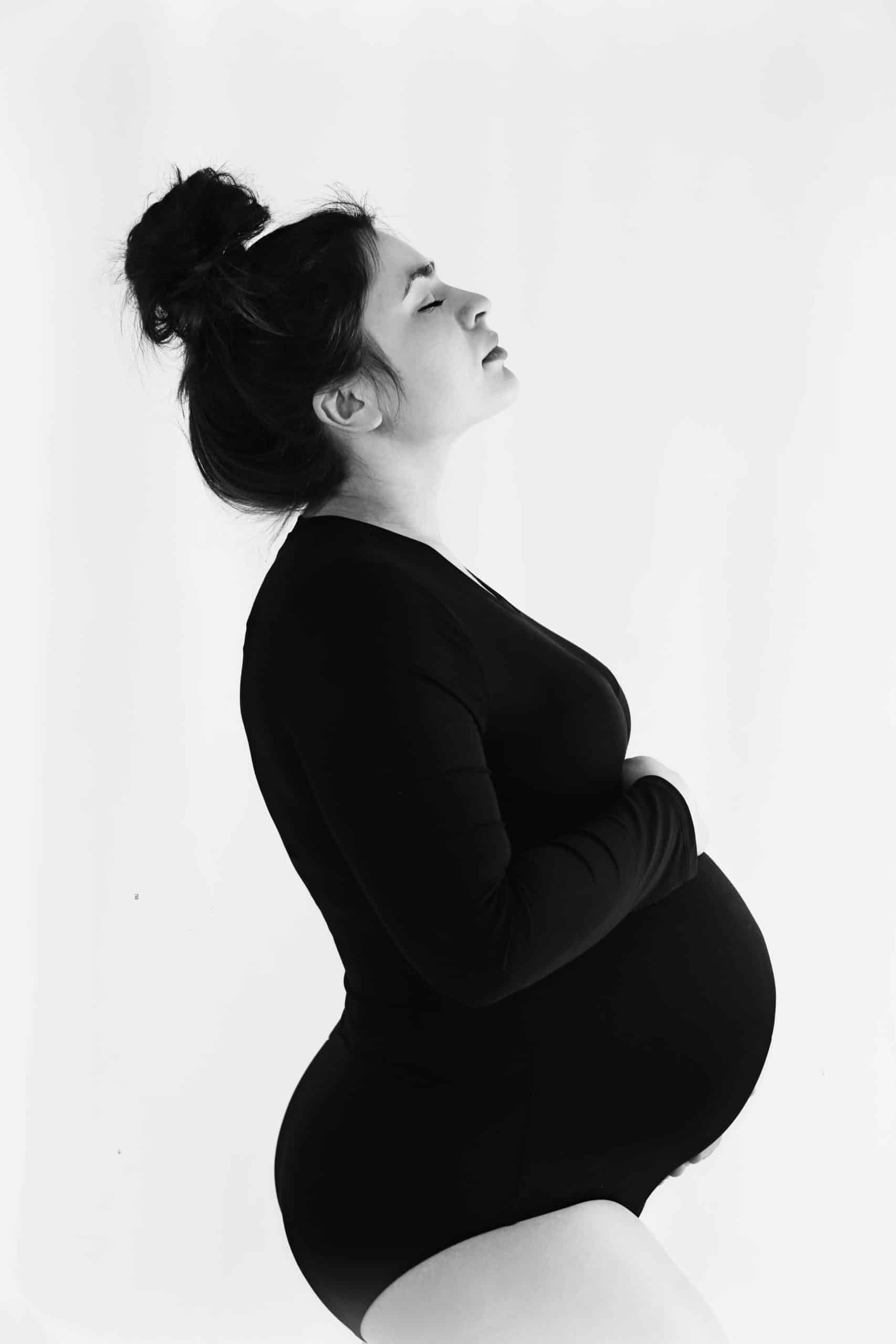 Zauberhaftes Schwangerschaftsfoto: Hochschwangere Frau im schwarzen Body im Fotostudio Quakenbrück