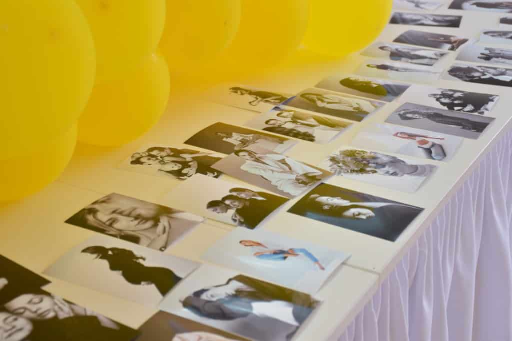 Verschiedene Abzüge auf einem weißen Tisch im Fotostudio Quakenbrück, umgeben von gelben Ballons.