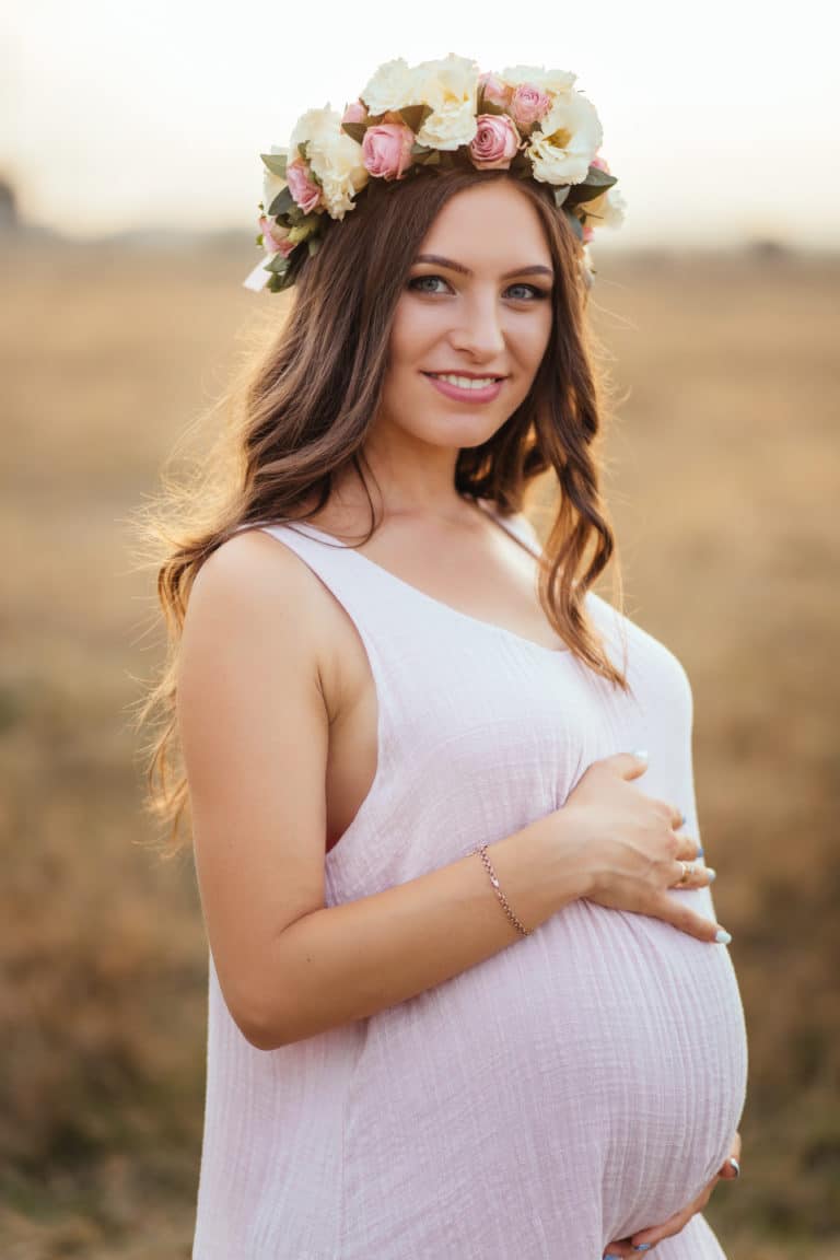 Natürliche Schönheit: Schwangere Frau mit Blumenkranz bei einem Fotoshooting.