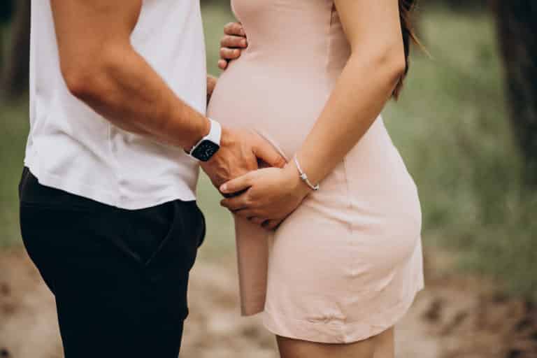 Mann und Frau halten liebevoll den Babybauch bei einem Fotoshooting.