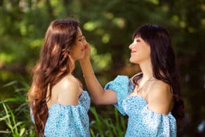 Zwei schöne Frauen in blauen Kleidern lächeln sich an.