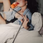 Natürliches Portrait einer Frau, die in einem der grünen Parks von Köln sitzt, umgeben von lebhafter Natur und belebter Stadtatmosphäre