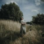 Natürliches Portrait einer Frau, die in einem der grünen Parks von Köln sitzt, umgeben von lebhafter Natur und belebter Stadtatmosphäre