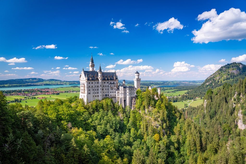 Das märchenhafte Schloss Neuschwanstein in den bayerischen Alpen, umgeben von dichten Wäldern und schroffen Bergen. Seine markante Architektur und die malerische Umgebung machen es zu einer der bekanntesten Sehenswürdigkeiten Deutschlands.