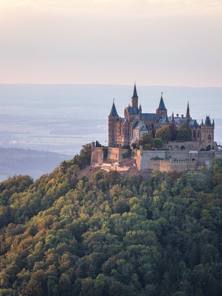 Majestätisches Schloss Hohenzollern auf seinem Berggipfel, umgeben von malerischen Wäldern und weiten Landschaften – ein beeindruckendes Wahrzeichen der deutschen Geschichte und ein atemberaubender Ort für Fotoshootings.