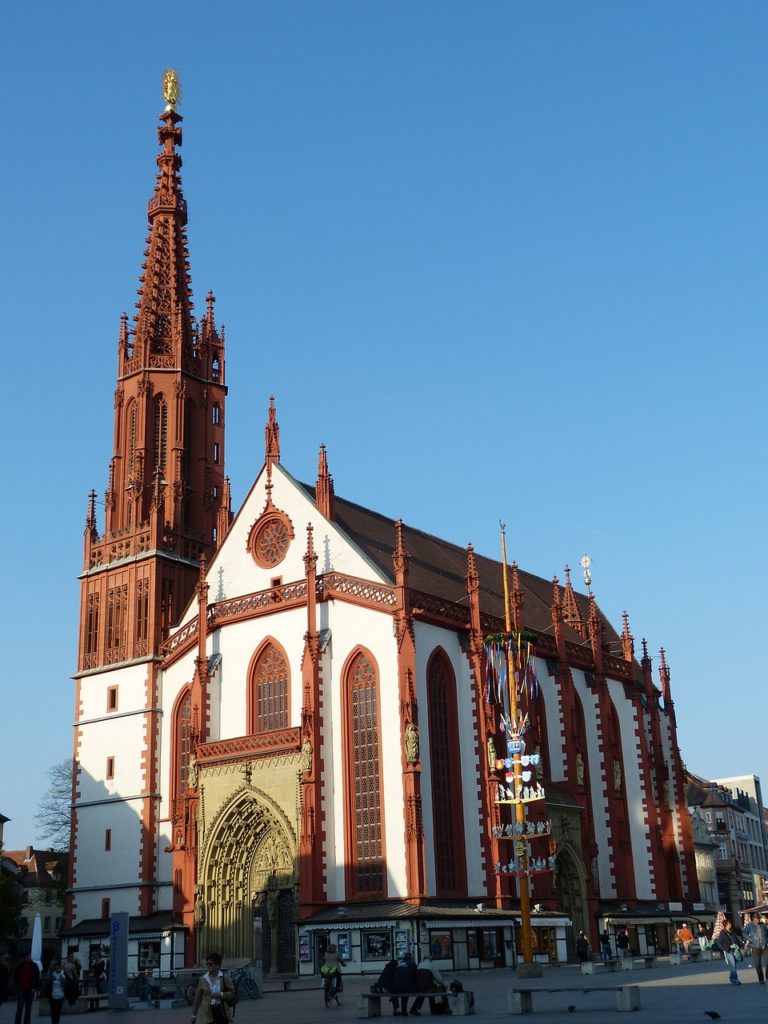 Die Würzburger Marienkapelle ragt unter einem strahlend blauen Himmel empor, ihre markanten gotischen Türme heben sich eindrucksvoll gegen das klare Firmament ab.