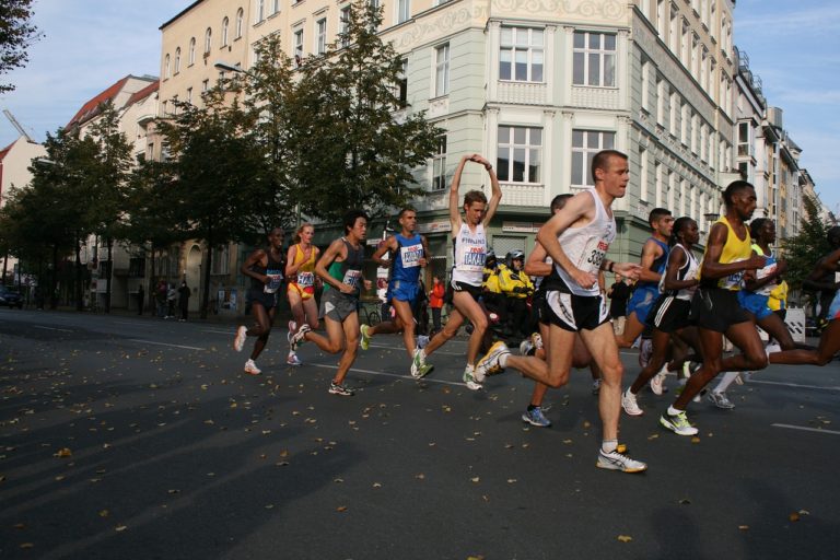 Läufer in Aktion während eines Stadtmarathons, aufgenommen in einer urbanen Umgebung mit Herbstblättern auf der Straße.